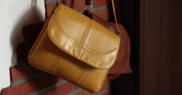 Novos sacos de mulheres amarelas e marrons pendurados na parede, close-up, lentidão. Bolsas de couro no corredor - Filmagem, Vídeo