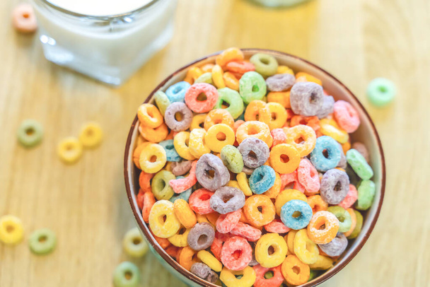 Ciotola di cereali colorati per bambini e latte isolato su tavolo in legno con spazio di testo - Foto, immagini