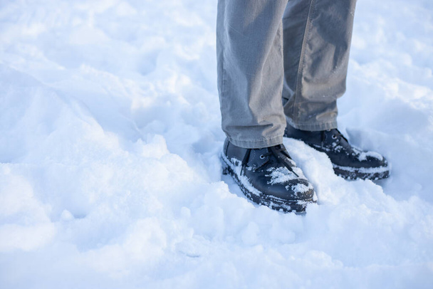 Pies en la nieve en invierno. Los zapatos están cubiertos de nieve. En clima frío con zapatos de cuero en la nieve - Foto, Imagen