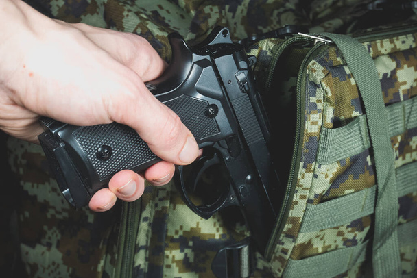 Man is putting in a military backpack Pistol or Gun - Фото, зображення
