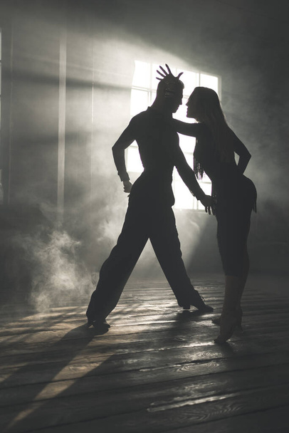 Couple of two professional ballroom dancers is dancing on loft studio. Beautiful art performance with heavy smoke. Sport life concept. Passion and emotional dance. - Foto, Imagem