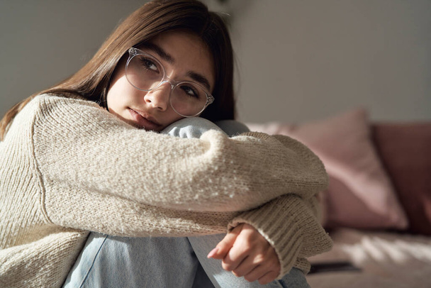Gros plan d'adolescente caucasienne coûteuse assise sur le lit et regardant ailleurs - Photo, image