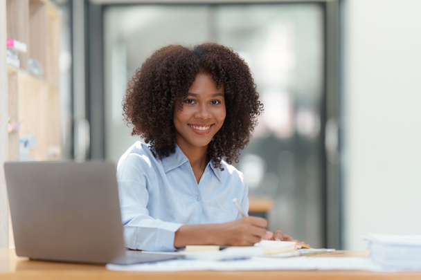 Νεαρή Αφροαμερικανίδα επιχειρηματίας που εργάζονται με φορητό υπολογιστή στο γραφείο, Εστίαση στο φορητό υπολογιστή οθόνη, διαβάζοντας ενδιαφέρον άρθρο σε απευθείας σύνδεση και τα οικονομικά. - Φωτογραφία, εικόνα
