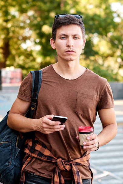 człowiek spacer trzymać telefon komórkowy i na wynos dostawa papieru filiżanka kawy - Zdjęcie, obraz
