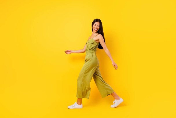 Full body profile portrait of adorable positive girl walk toothy smile isolated on yellow color background. - Photo, image