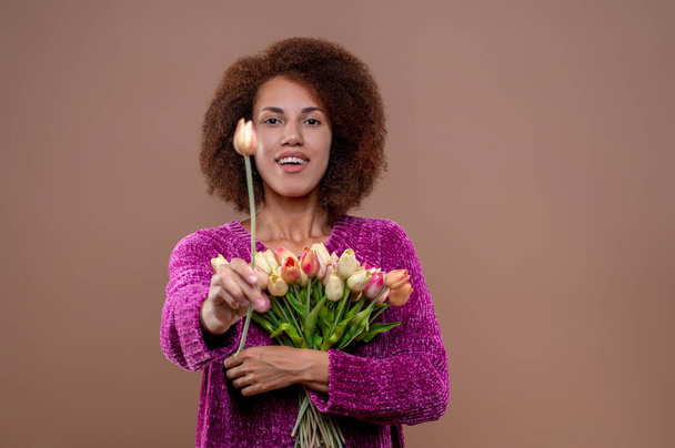Kukkien kanssa. Hymyilevä kaunis nuori nainen, jolla on kasa kukkia - Valokuva, kuva
