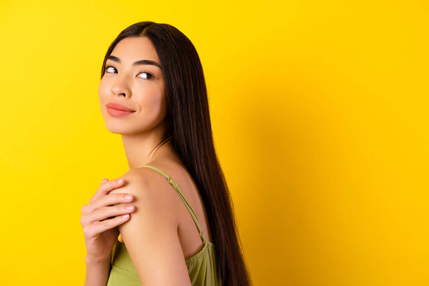 Photo of cute pretty young lady wear green outfit looking back empty space isolated yellow color background. - Foto, imagen