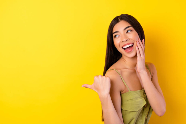 Photo of sweet dreamy young girl dressed clothes pointing thumb empty space isolated yellow color background. - Фото, зображення