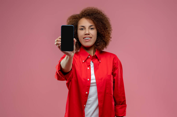 Gadget. Jeune femme aux cheveux bouclés avec un smartphone dans les mains - Photo, image
