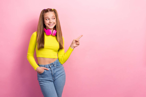 Photo of nice adorable schoolgirl dressed yellow long sleeve headphones indicating look empty space isolated on yellow color background. - Foto, Imagem