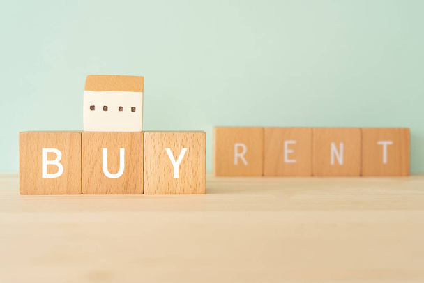 Buying house; Wooden blocks with "BUY RENT" text of concept and a house toy. - Photo, Image