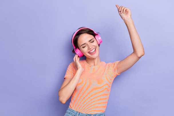 Photo of cheerful glad overjoyed lady wear striped trendy clothes raise hand listen song melody isolated on purple color background. - Zdjęcie, obraz