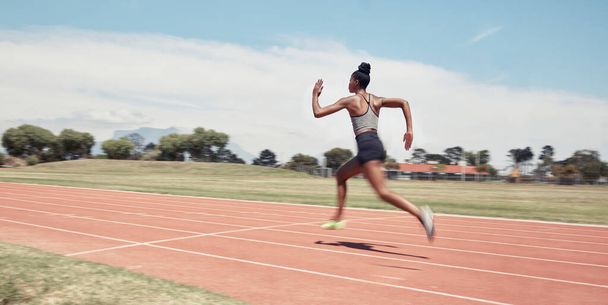 Runner, fitness and fast black woman in stadium for professional race, competition or training. Sprint, performance and champion running athlete on sport ground with blur speed movement or motion - Fotó, kép