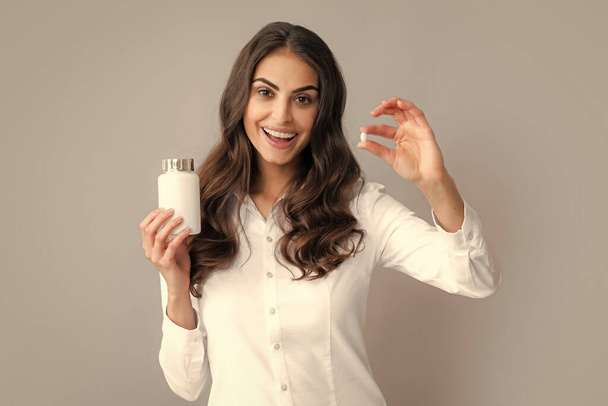 Nő üvegtablettákkal. Csinos nő kezében egy üveg étrend-kiegészítő, vitaminok és ásványi anyagok. Egészség, bőr- és testápolás - Fotó, kép