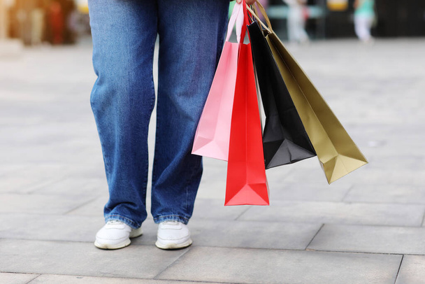 Oříznutý portrét nerozpoznatelné ženy s barevnými nákupními taškami na městském nákupním centru pozadí. Nákupy, černý pátek, slevy, koncept prodeje. Online nákupní koncept, Sezónní prodej - Fotografie, Obrázek