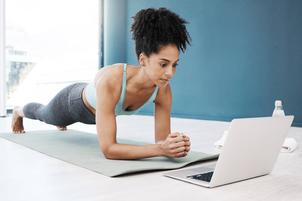 Webinaire bien-être, fitness et yoga sur ordinateur portable pour femme noire en bonne santé et jeune en position de planche de corps. Focus, équilibre et pleine conscience en ligne en classe d'exercice avec la fille sur le sol à la maison pour la santé - Photo, image