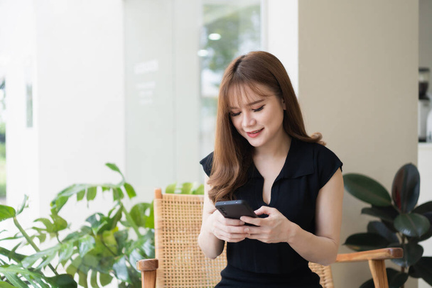 Ázsiai dolgozó nő tart mobiltelefon szöveges üzenet, chat beszélgetés vagy a közösségi média. Üzletasszony használja okostelefon böngésző web, olvasni e-könyv, kereskedelmi készletek. Kommunikációs technológiai koncepció. - Fotó, kép
