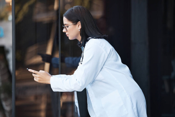 Woman, doctor and phone on hospital break, clinic balcony or consulting on social media, internet research or schedule planning. Thinking healthcare worker, mobile technology and 5g calendar app. - Foto, afbeelding