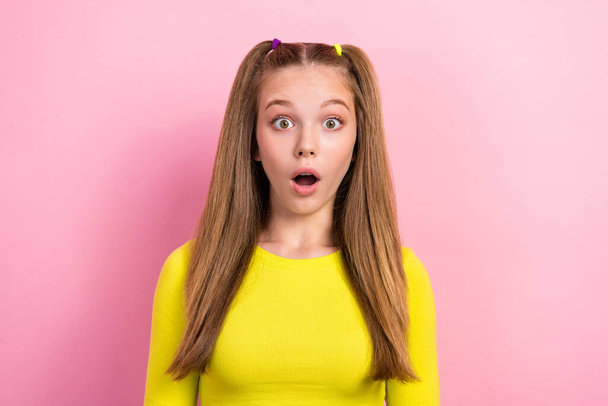 Photo of good mood adorable schoolgirl with ponytails dressed yellow long sleeve staring open mouth isolated on yellow color background. - 写真・画像