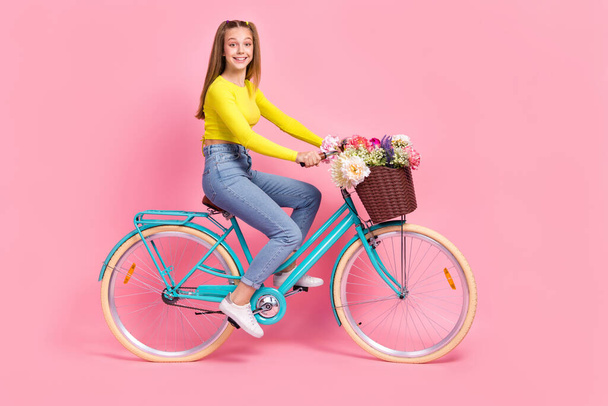 Full length photo of cute adorable schoolgirl wear yellow crop top driving bike isolated pink color background. - Fotó, kép