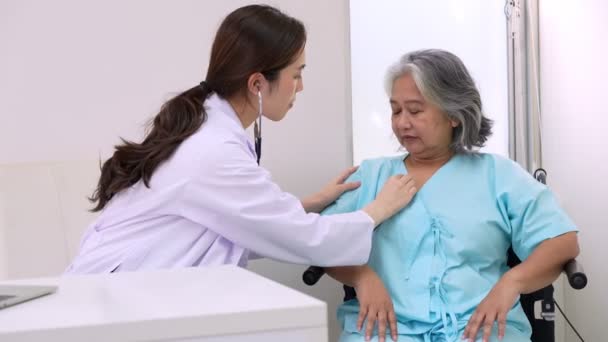 Artsen onderzoeken hart met een stethoscoop en praten met een oudere vrouw in een kliniek voor controle jaarlijkse controle, Geneeskundige gezondheidszorg en ziektekostenverzekering concept. - Video