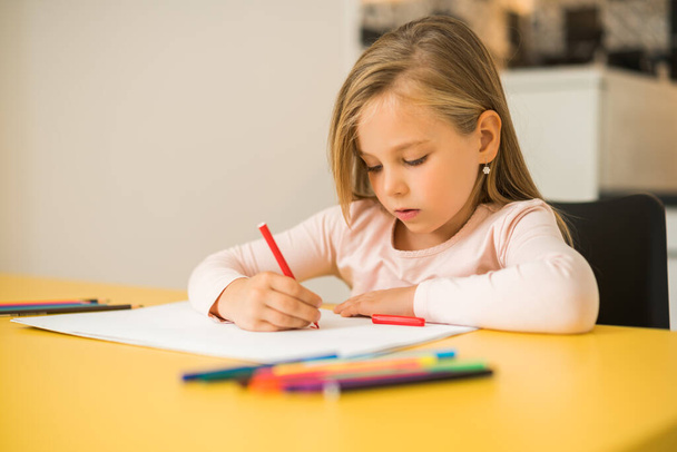 Beautiful little girl enjoys drawing at her home. - Photo, Image