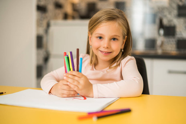 Beautiful little girl enjoys drawing at her home. - 写真・画像