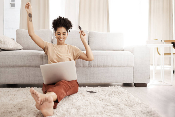 Black woman, laptop and happy with credit card, ecommerce and approved loan in lounge. Young female, lady and digital device for success, online banking and happiness with smile, joy and living room - Valokuva, kuva
