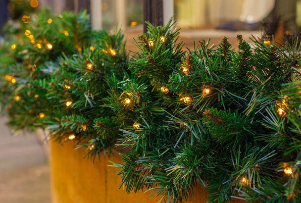 eine einfache Girlande aus Weihnachtsbaumzweigen mit elektrischen Lichtern. draußen Straße festlich dekorieren, Winterurlaub - Foto, Bild