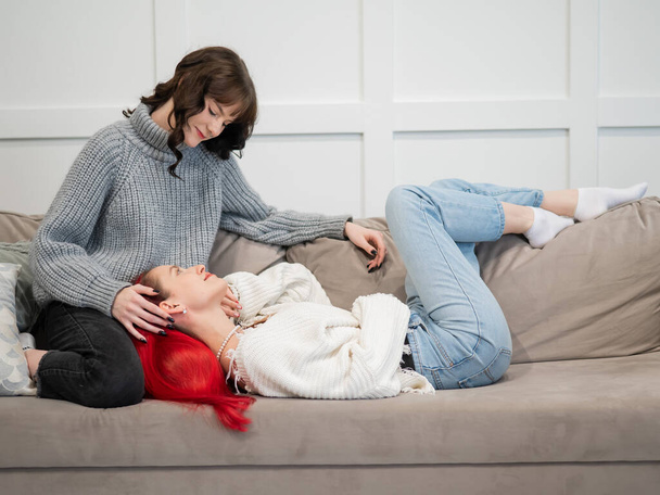 Chicas jóvenes abrazándose mientras yacen en el sofá. Amor unisexual - Foto, imagen
