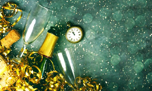 Feliz Año Nuevo. Vista superior de la botella de champán, dos copas, serpentinas doradas, reloj antiguo y luces de Navidad con espacio para texto sobre fondo grunge. Año Nuevo concepto de celebración víspera fondo - Foto, imagen