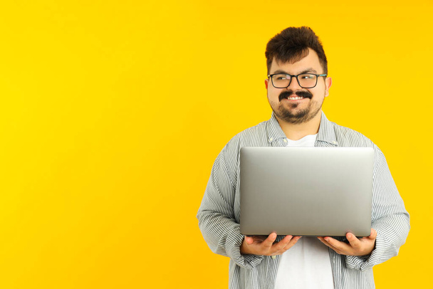 Concept van mensen, jonge dikke man met laptop op gele achtergrond - Foto, afbeelding