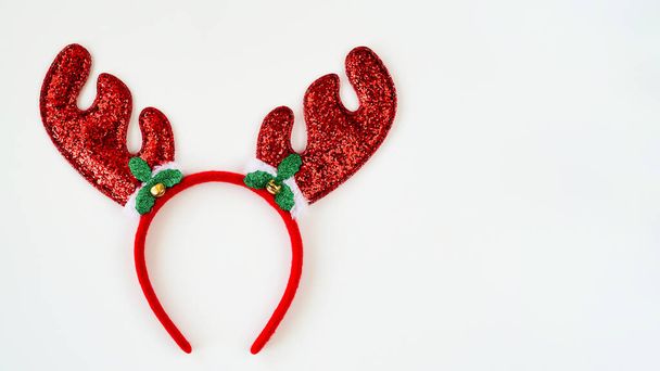 Nahaufnahme von rot glänzenden Weihnachtshörnern auf weißem Hintergrund, dekoratives Stirnband, Draufsicht, flache Lage, Kopierraum. Dekorkonzept für Weihnachten oder Silvesterparty.Weihnachtsgeweihe - Foto, Bild