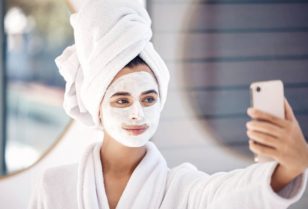 Γυναίκα, μάσκα προσώπου και τηλεφωνική selfie μετά το πρωινό ντους, ευεξία και υγιεινή περιποίηση της επιδερμίδας, προϊόν μακιγιάζ και καθαρισμός στο μπάνιο στο σπίτι. Ομορφιά, μάσκα προσώπου καλλυντικά και γυναικεία λήψη φωτογραφιών στο κινητό. - Φωτογραφία, εικόνα
