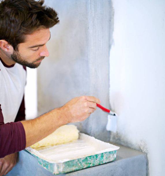 Ügyes a ház körül. egy fiatalember, aki falat fest a házban. - Fotó, kép
