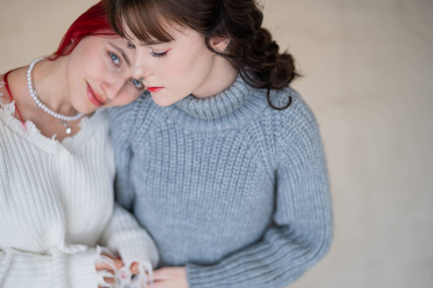 Portrait of two tenderly hugging women dressed in sweaters. Lesbian intimacy - Фото, изображение