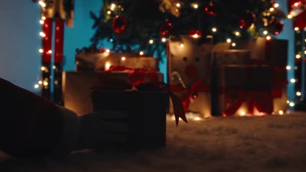 Mão de Papai Noel eu entregar a caixa de presente de Natal sob a árvore na noite. - Filmagem, Vídeo