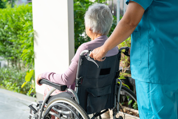 Verzorger hulp en zorg Aziatische senior of oudere oude dame patiënt zit in rolstoel op hellingbaan bij verpleegkundige ziekenhuis, gezond sterk medisch concept - Foto, afbeelding
