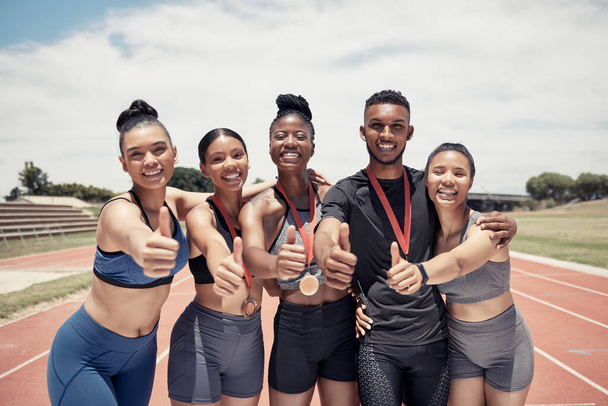 Zespół, kciuki do góry i zwycięzca sportu z medalem, biegacza i szczęśliwy w portret, sukces i zwycięstwo na torze wyścigowym. Młody czarny mężczyzna, różnorodność i kondycja, atleta wygrywa ćwiczeniami i współpracą - Zdjęcie, obraz