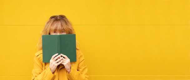 mujer sobre fondo amarillo con libro, lectura - Foto, Imagen