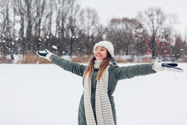 Happy young woman playing with snow tossing it outdoors wearing warm knitted clothes and having fun enjoying weather. Seasonal activities - Fotografie, Obrázek