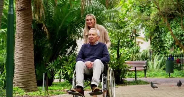 Egy nő sétál a rangidős apjával kerekesszékben a természetben, egy zöld kertben Ausztráliában. Boldog, testmozgás és a fogyatékkal élő idős férfi sétál felnőtt lányával a szabadtéri parkban friss levegőt szívni - Felvétel, videó
