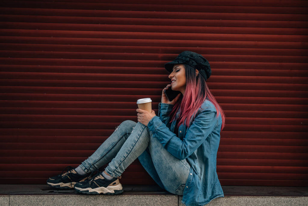девушка разговаривает по мобильному телефону на улице со слепым на красном фоне - Фото, изображение