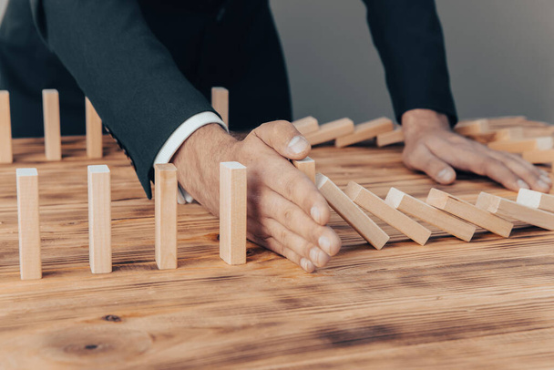 Risk and Strategy in Business, Image of hand stopping falling collapse wooden block dominoes effect from continuous toppled bloc - Fotoğraf, Görsel