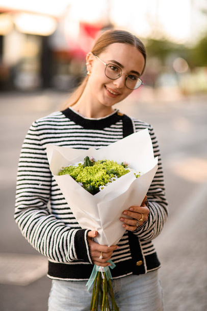 beautiful smiling woman holds bouquet of curly green chrysanthemums and small white daisy-like chrysanthemums in wrapping paper in her hands - Photo, image