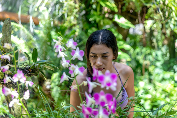 Sexy jeune femme regardant les orchidées et les plantes bohèmes du musée vivant et de la serre à Xcaret Park au Mexique, un endroit de la riviera Maya très visité par les touristes. - Photo, image