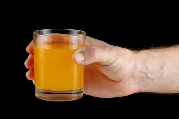 Jugo de naranja en un vaso en la mano. Jugo de mano. - Foto, Imagen
