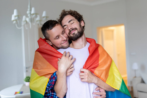 Affectueux couple gay masculin à l'intérieur. Un homme embrassant son petit ami par derrière à la maison. couple gay célébrant fierté mois - Photo, image