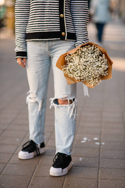 cropped photo of woman with bouquet in her hand. Focus on bouquet with white gypsophila flowers - Valokuva, kuva