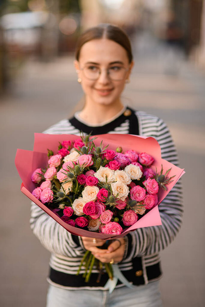 selective focus on flowers of bouquet with white and pink roses and thistles in hands of woman - Photo, image